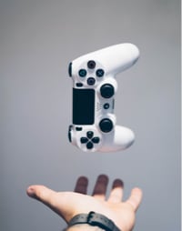 a game controller in mid air with a hand underneath it